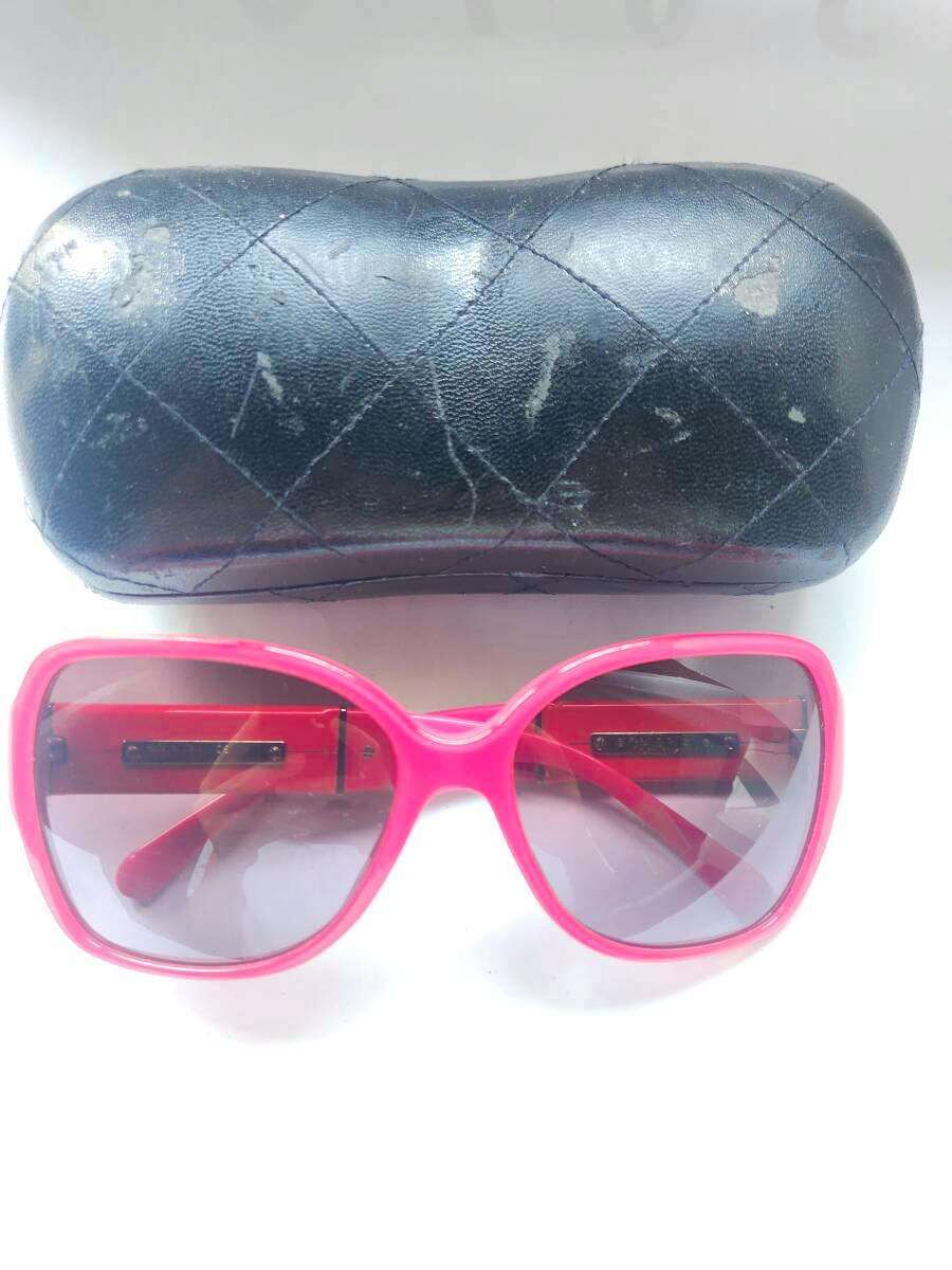 Pink plastic women's sunglasses with gradient lenses displayed below a black quilted glasses case.