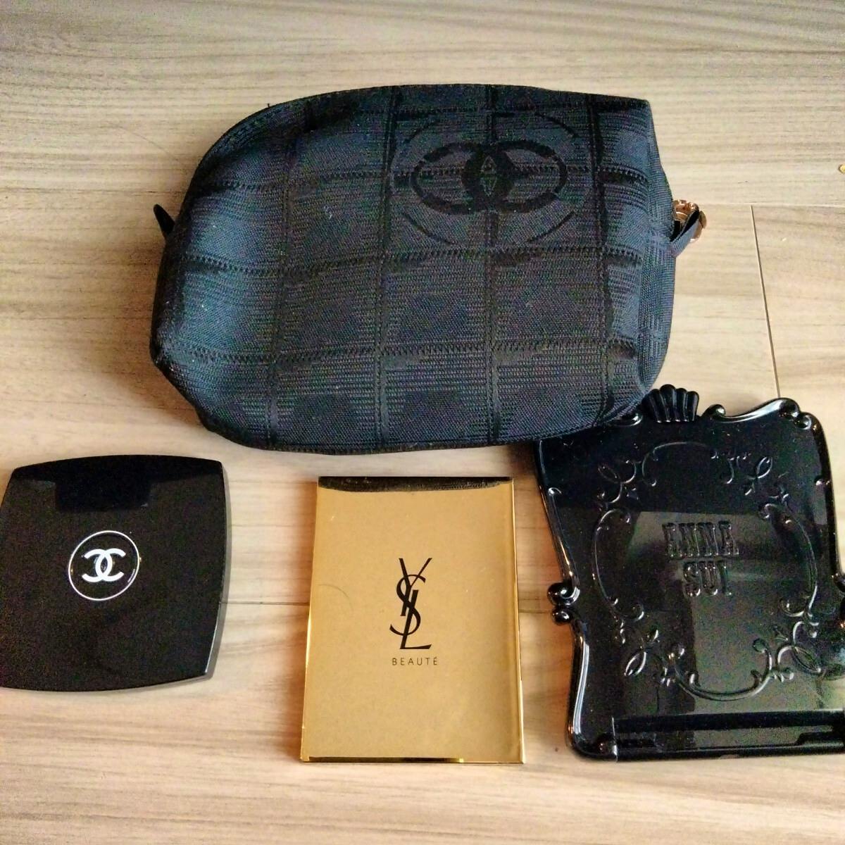Black canvas pouch with a stitched check pattern shown above three compact mirrors (Chanel, YSL, ANNA SUI) on a wood surface.