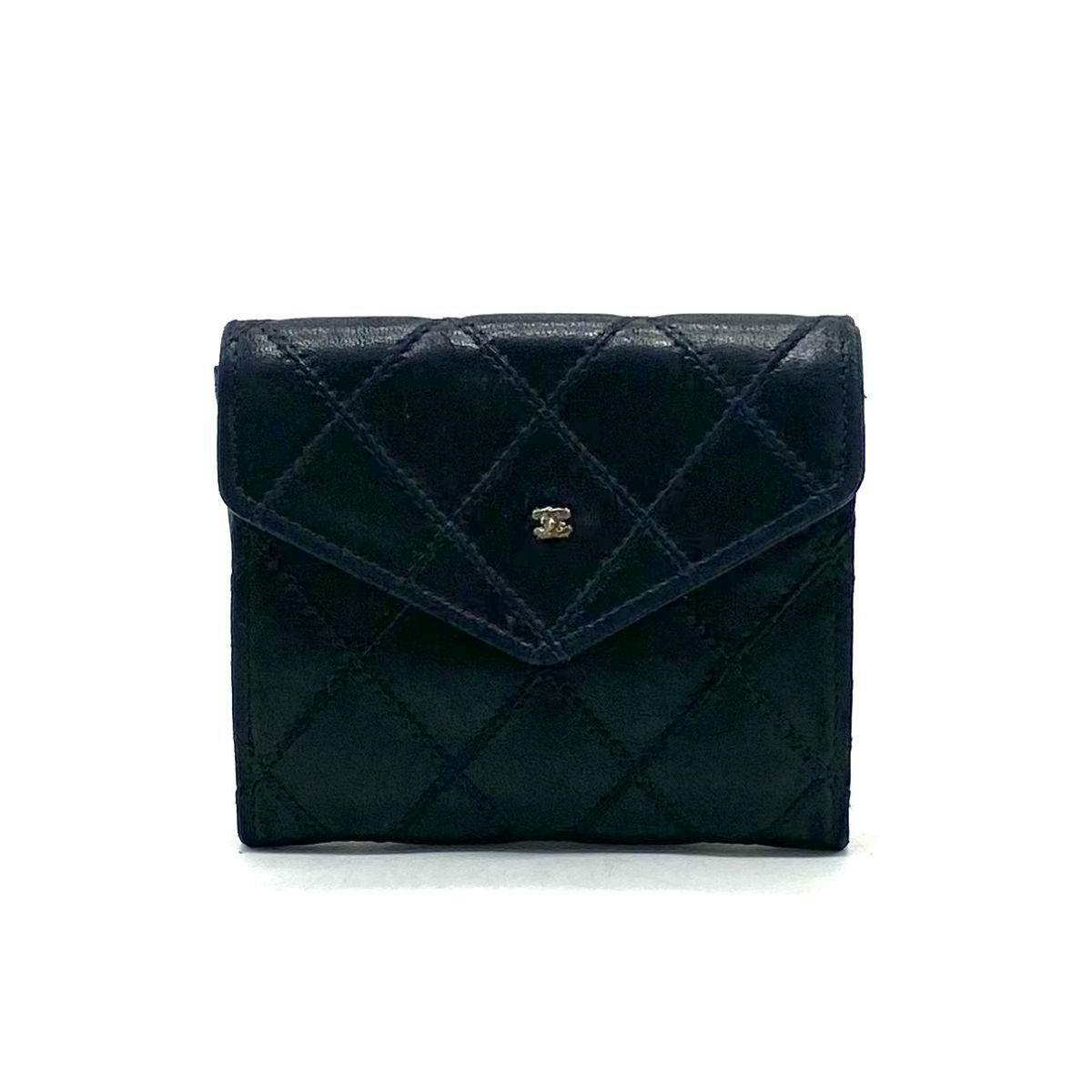 Front view of a black quilted leather CHANEL coin case with flap and small Coco double-C logo.