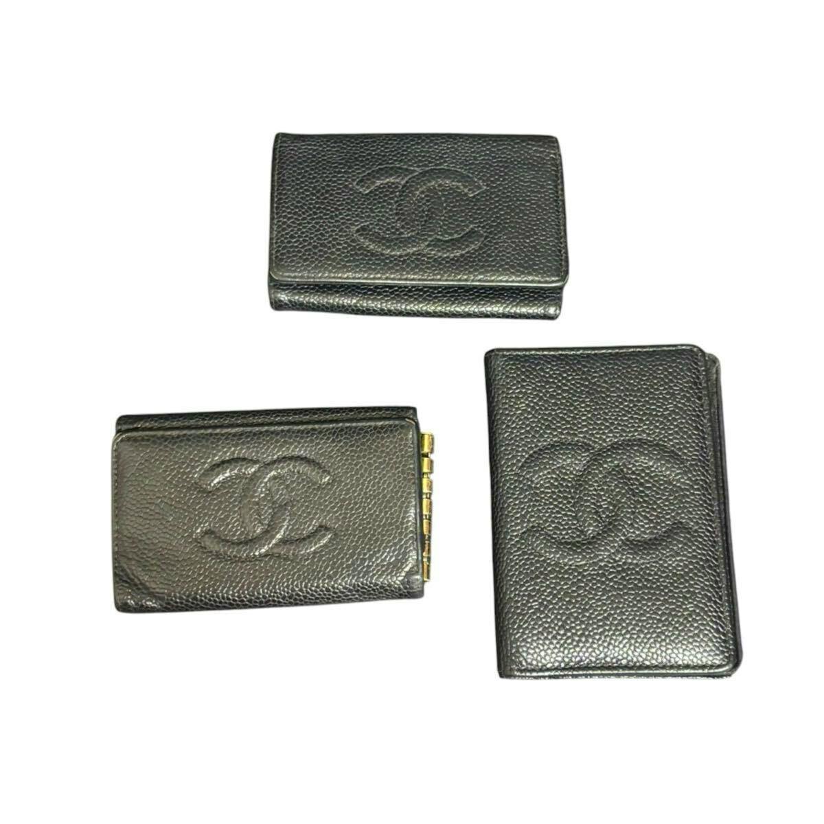 Three black Chanel leather small wallets/key/card cases with embossed CC logos arranged on a white background.