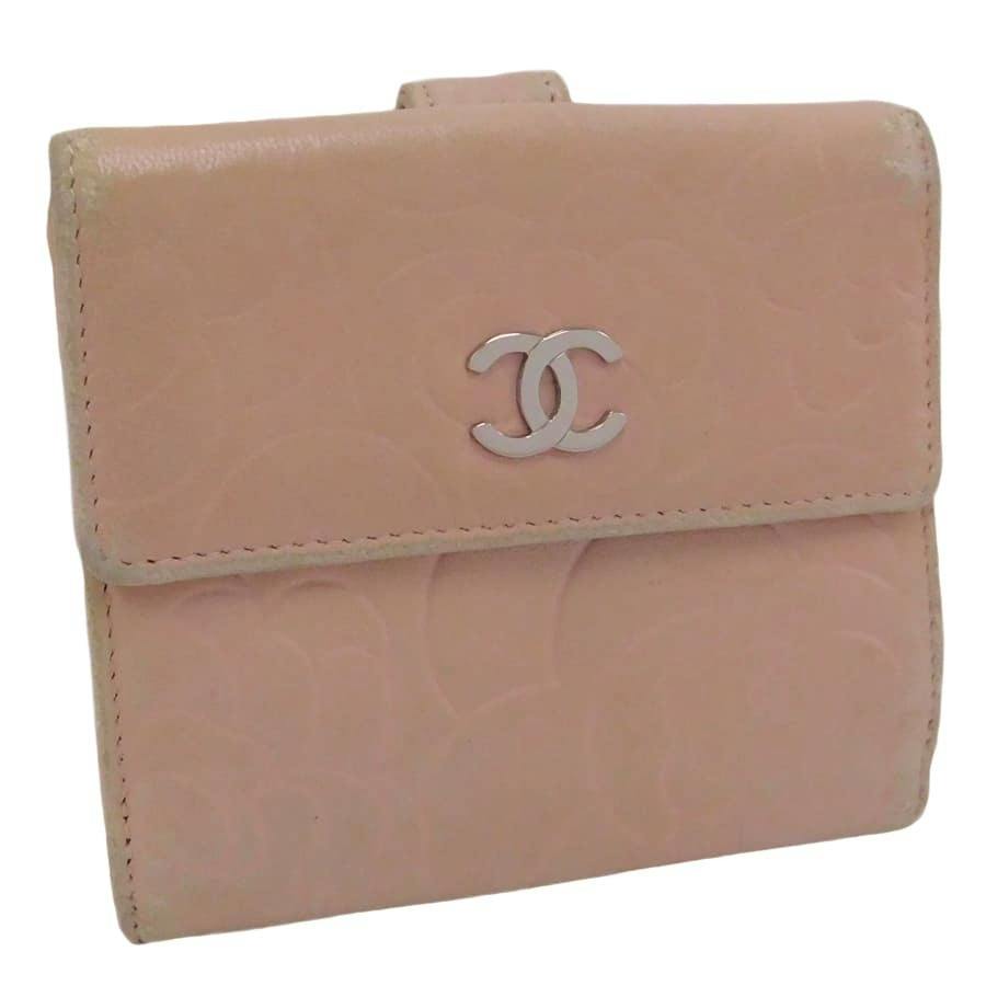 Front view of a CHANEL compact bi-fold wallet showing a metal CC logo and camellia embossing.