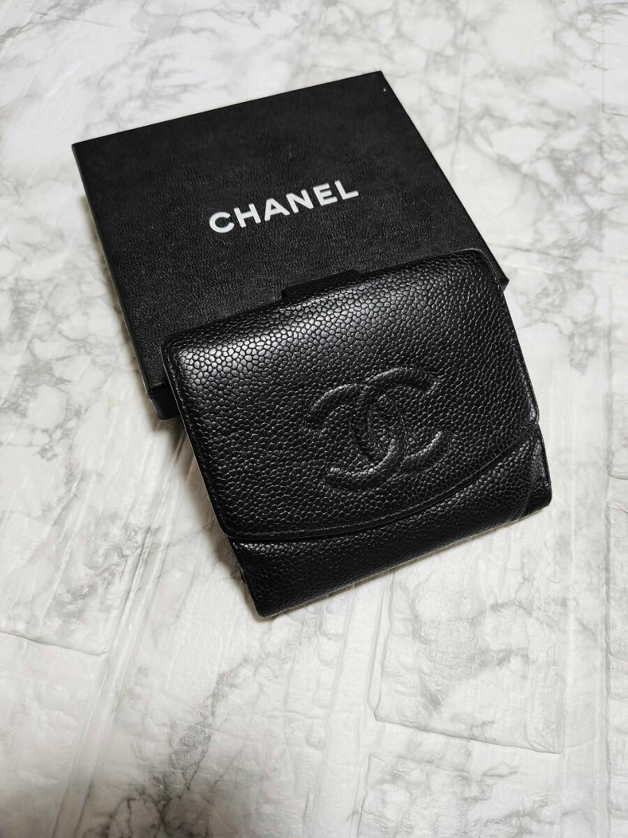Black CHANEL caviar cow leather wallet with embossed interlocking CC logo placed on a CHANEL box.