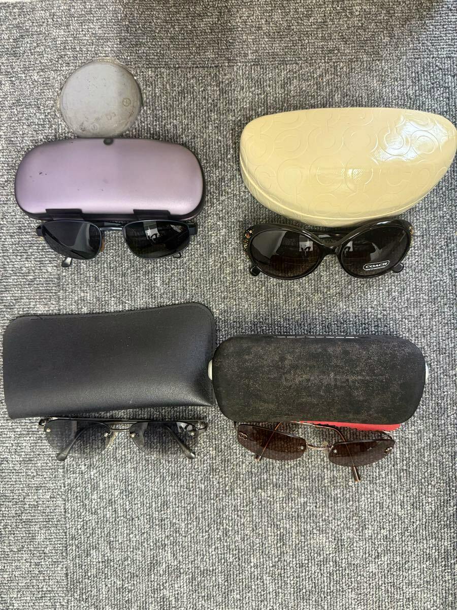 Four pairs of sunglasses with four cases arranged on a gray carpet.