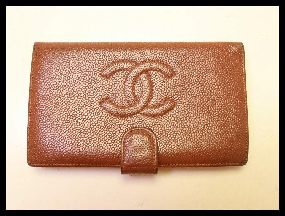 Closed brown CHANEL caviar leather long wallet with embossed interlocking CC logo and front tab closure.