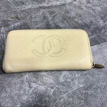 Beige CHANEL long zip-around wallet in caviar leather with stitched CC logo on the front and a gold zipper pull.
