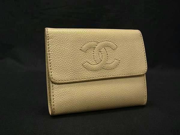 Beige CHANEL caviar leather trifold wallet with an embossed CC logo on the front, shown on a black background.