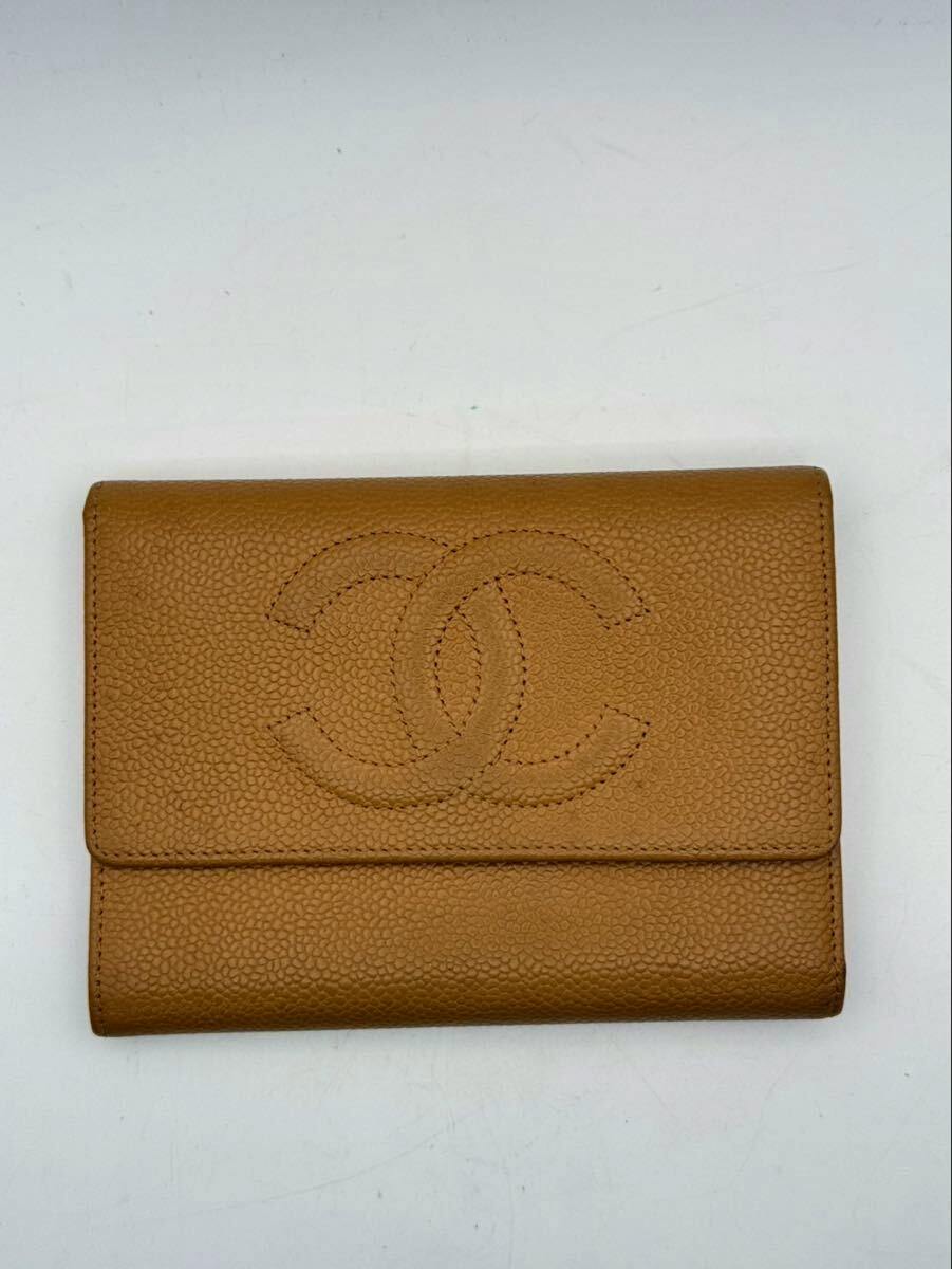 Closed camel-brown CHANEL caviar-skin trifold wallet showing the stitched CC logo on the front.