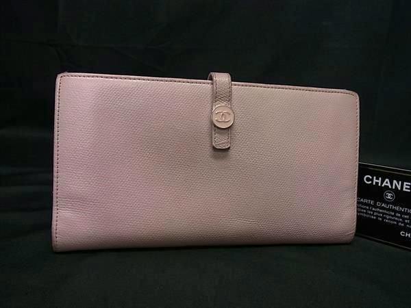 Pink CHANEL cow leather long bifold wallet with a Coco (CC) button strap closure photographed on a dark background.