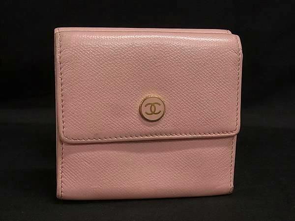 Light pink CHANEL leather trifold wallet with a round gold CC button on the front, shown against a black background.