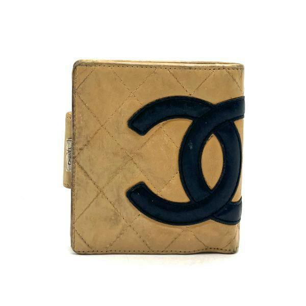 Front view of a beige quilted CHANEL cow leather wallet with a large black interlocking CC logo and a side snap closure.