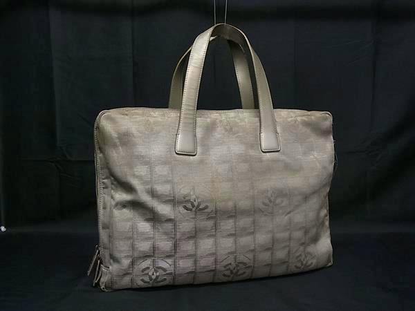 Greige Chanel Coco Mark New Travel Line canvas tote handbag shown front view against a black background.