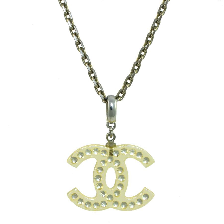 Close-up of the CHANEL necklace showing a clear plastic interlocking CC pendant studded with rhinestones on a metal chain.