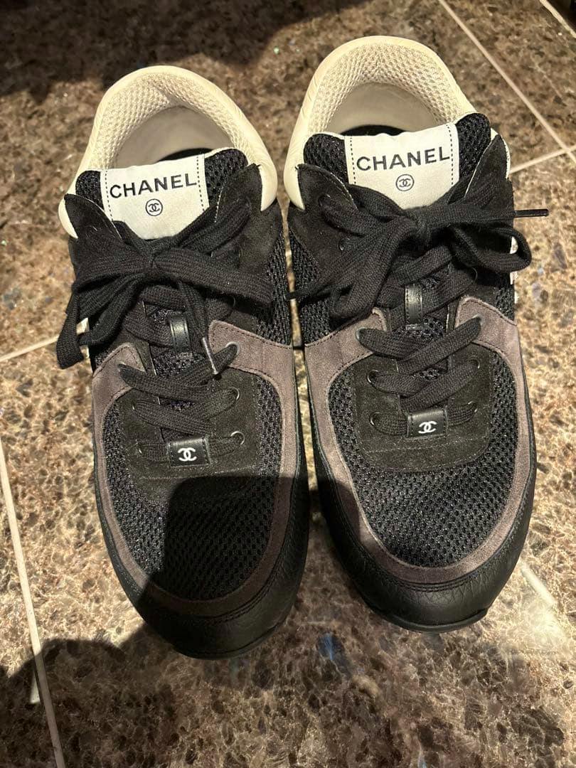Top-down photo of a pair of black CHANEL sneakers (size 43) showing the tongues with CHANEL labels and CC logos.