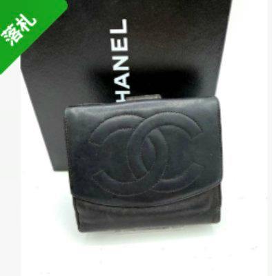 Black CHANEL compact bi-fold wallet with a large CC logo on the front placed in front of a CHANEL box.