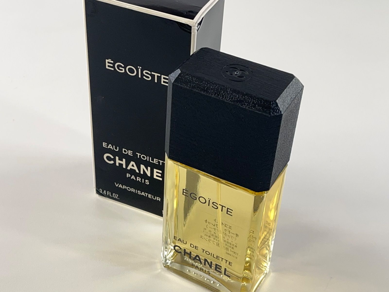 A Chanel Égoïste eau de toilette 100ml glass bottle with black cap displayed next to its box.