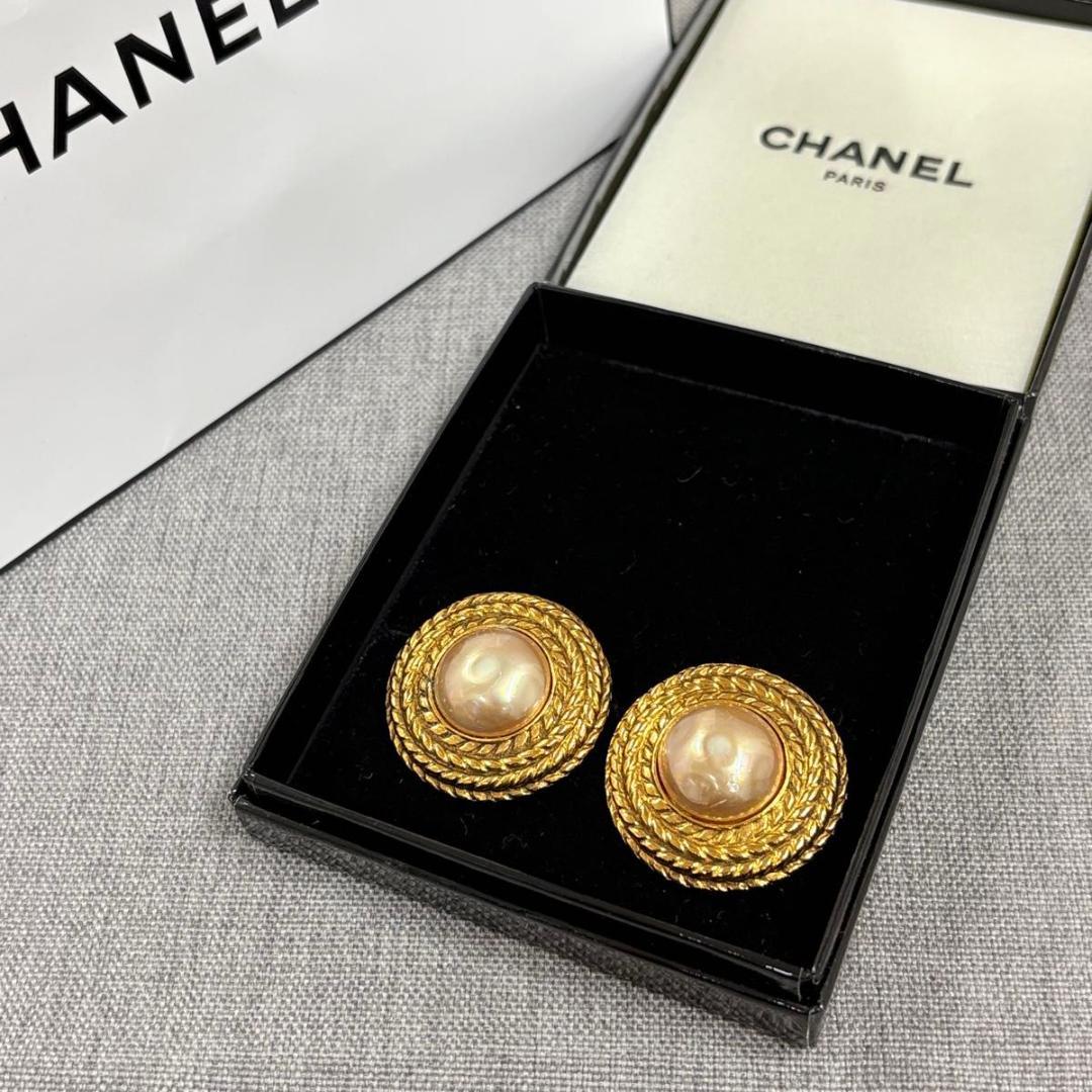 Pair of CHANEL gold-color faux pearl round earrings displayed in an open CHANEL jewelry box.