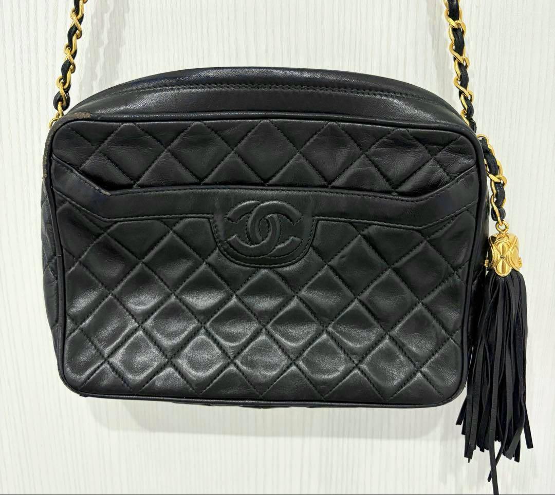 Front view of the black CHANEL Matelassé chain shoulder bag showing quilted pattern, CC logo, chain strap and black tassel.