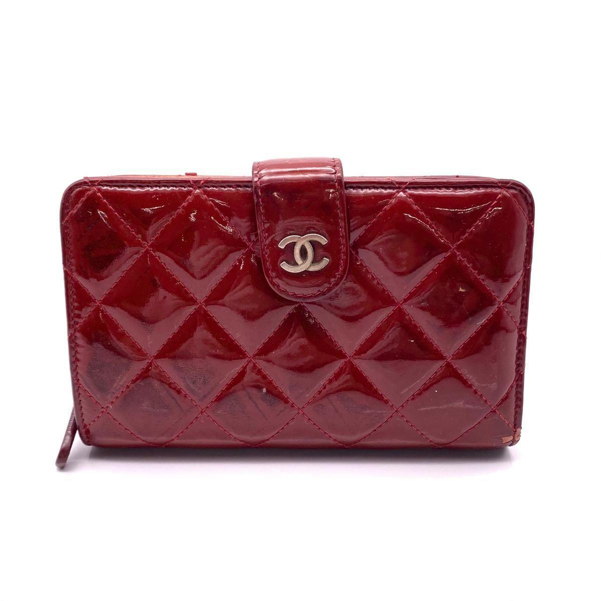 Front view of a red CHANEL Matelassé patent leather two-fold wallet with a CC clasp.