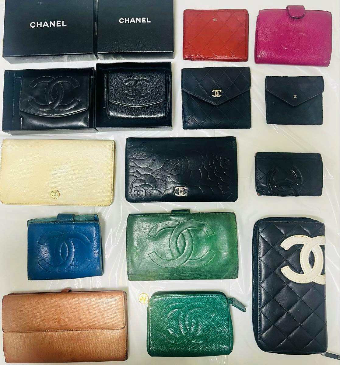 Several CHANEL wallets and small leather goods in various colors arranged flat on a surface, with some pieces shown inside black CHANEL boxes.