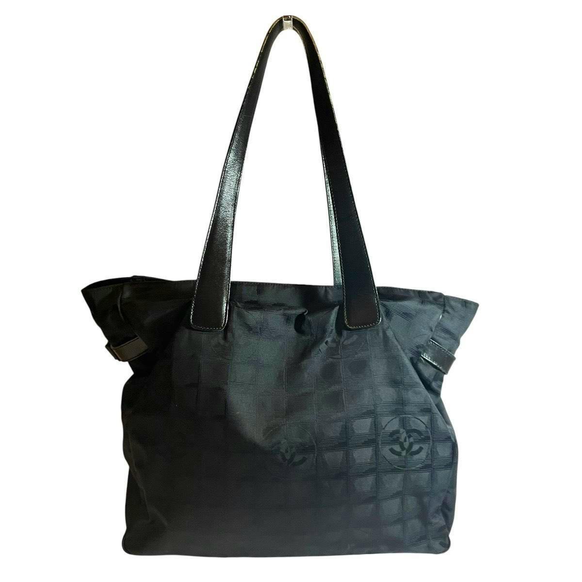 Front view of a black Chanel New Travel Line canvas tote bag with long leather shoulder straps on a white background.