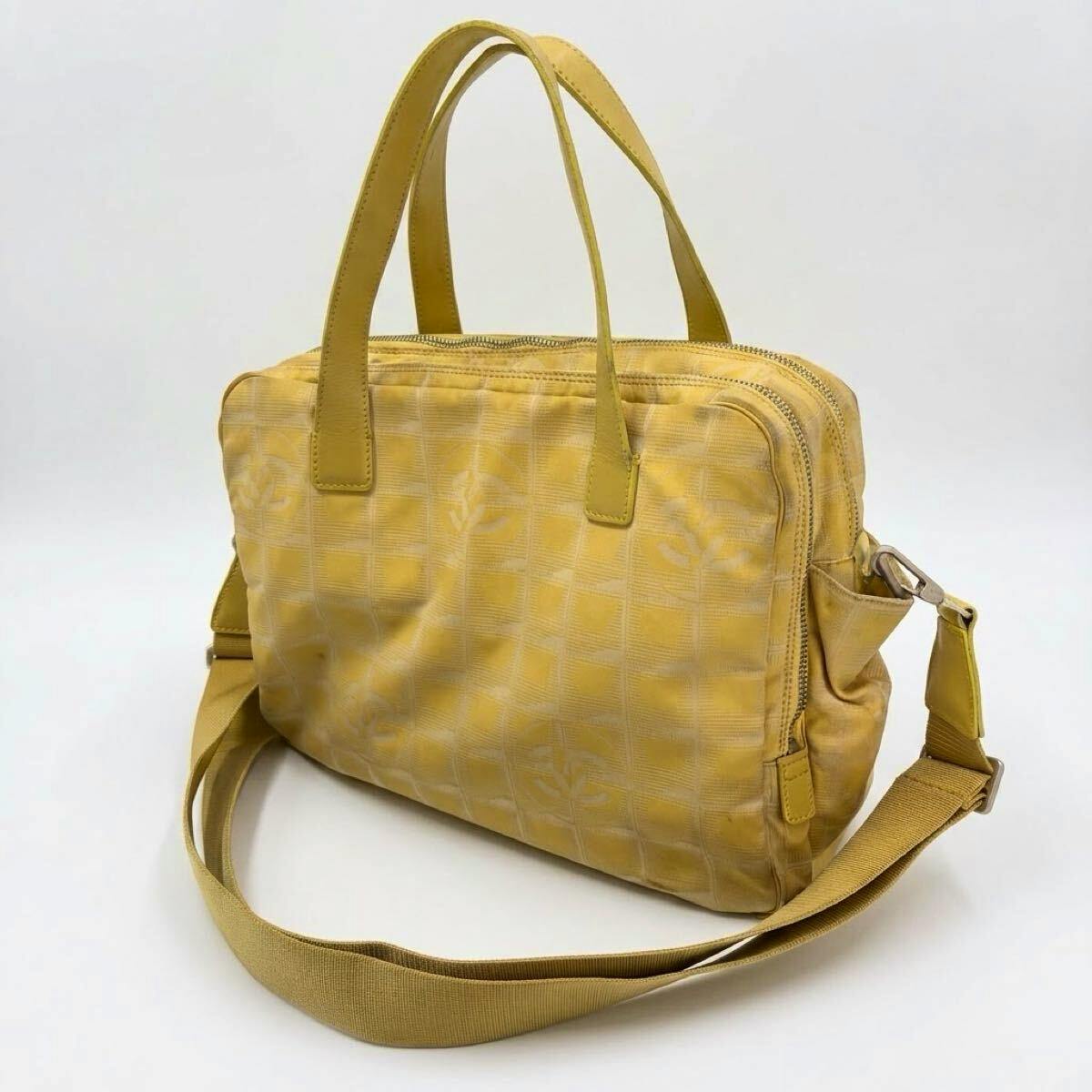 Yellow CHANEL New Travel Line canvas tote handbag with top handles and a detachable shoulder strap shown at a three-quarter angle.