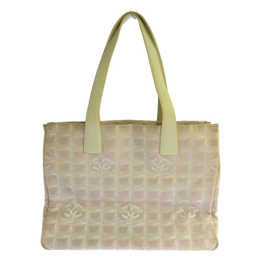 Beige CHANEL New Travel Line MM canvas tote bag with two top handles and a grid pattern of CC logos, front view.