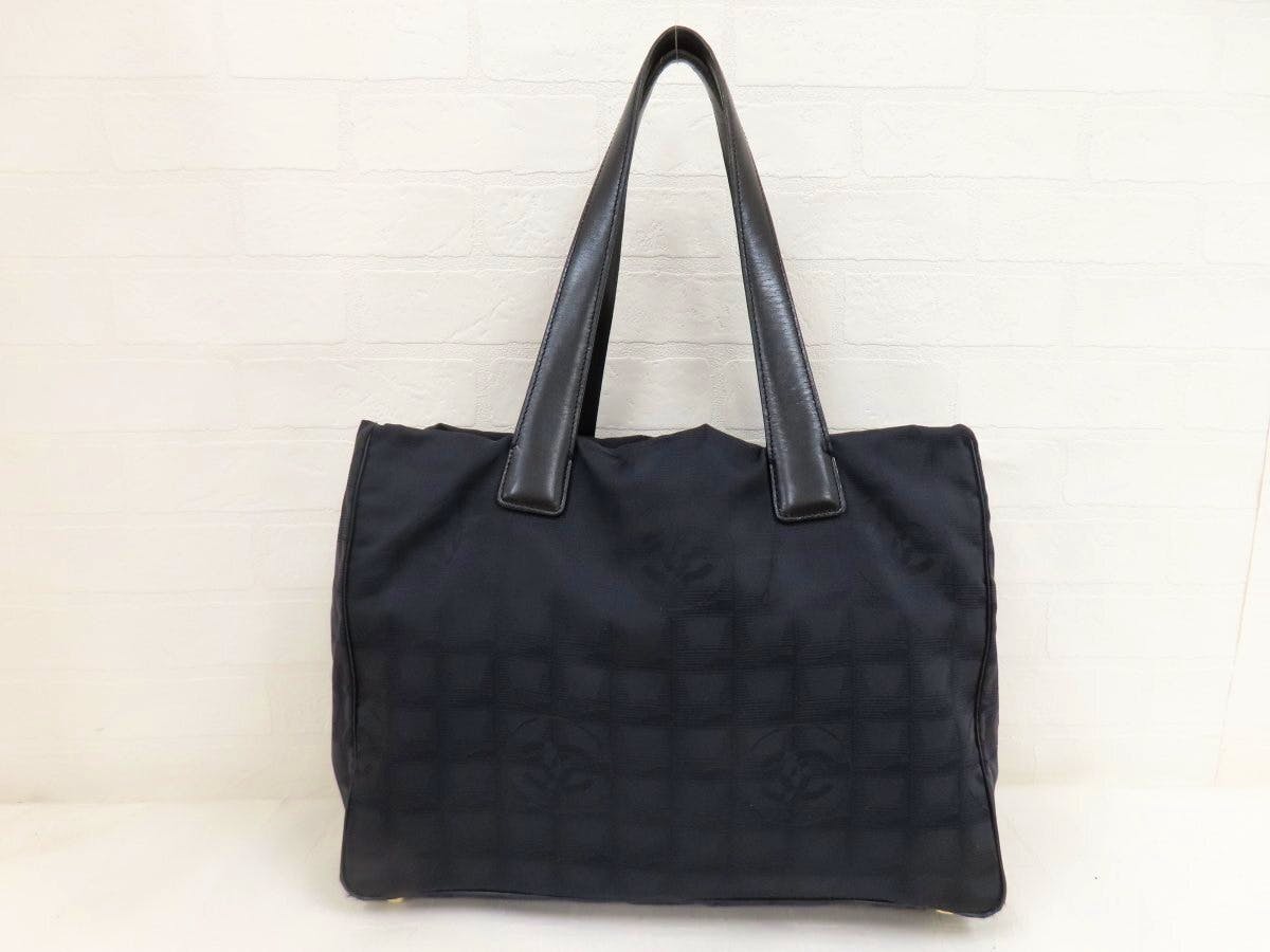 Front view of a black CHANEL tote bag with calf leather shoulder straps and a subtle CC pattern on the nylon body.