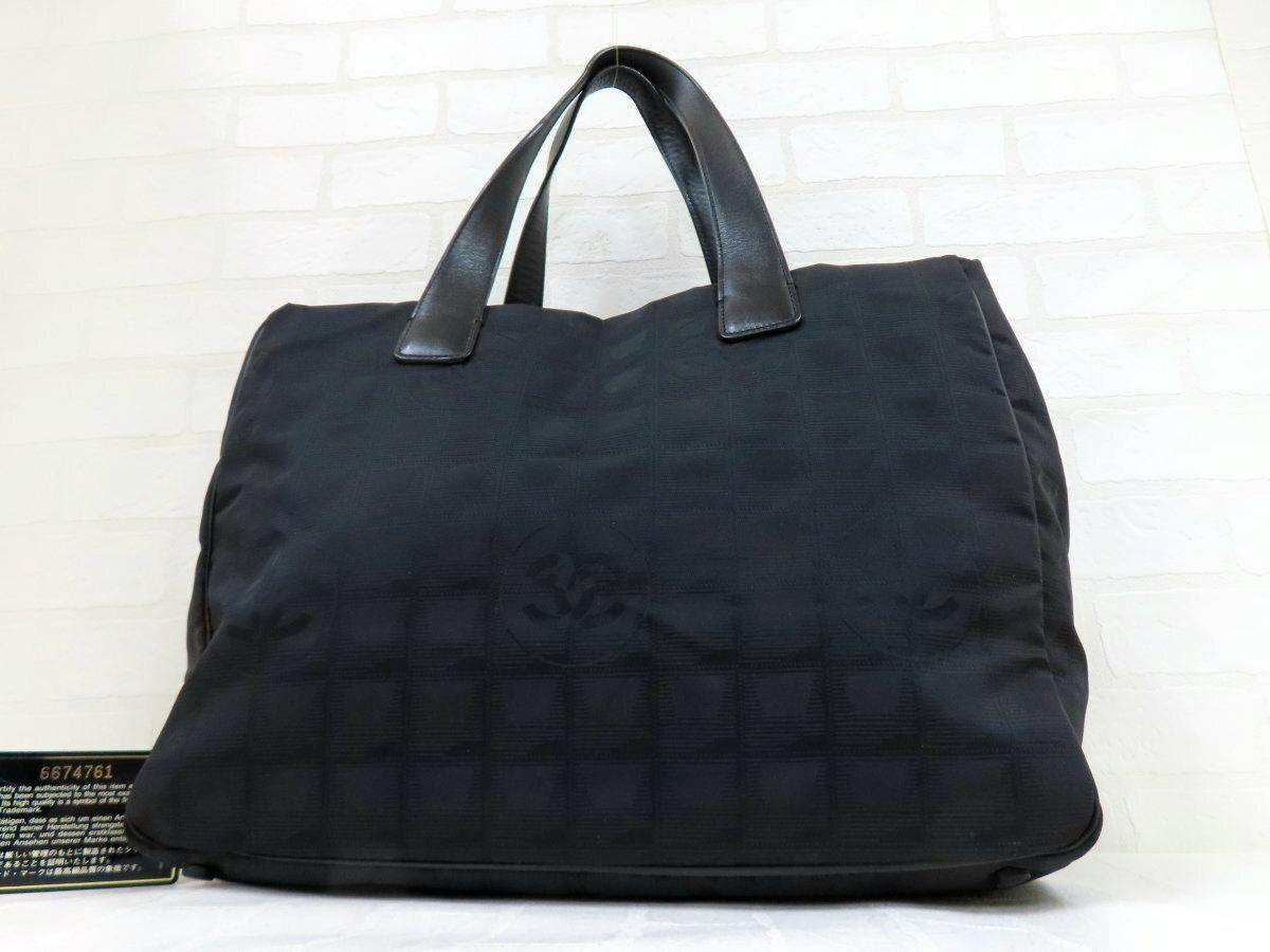 Front view of a black CHANEL nylon tote bag with leather handles.