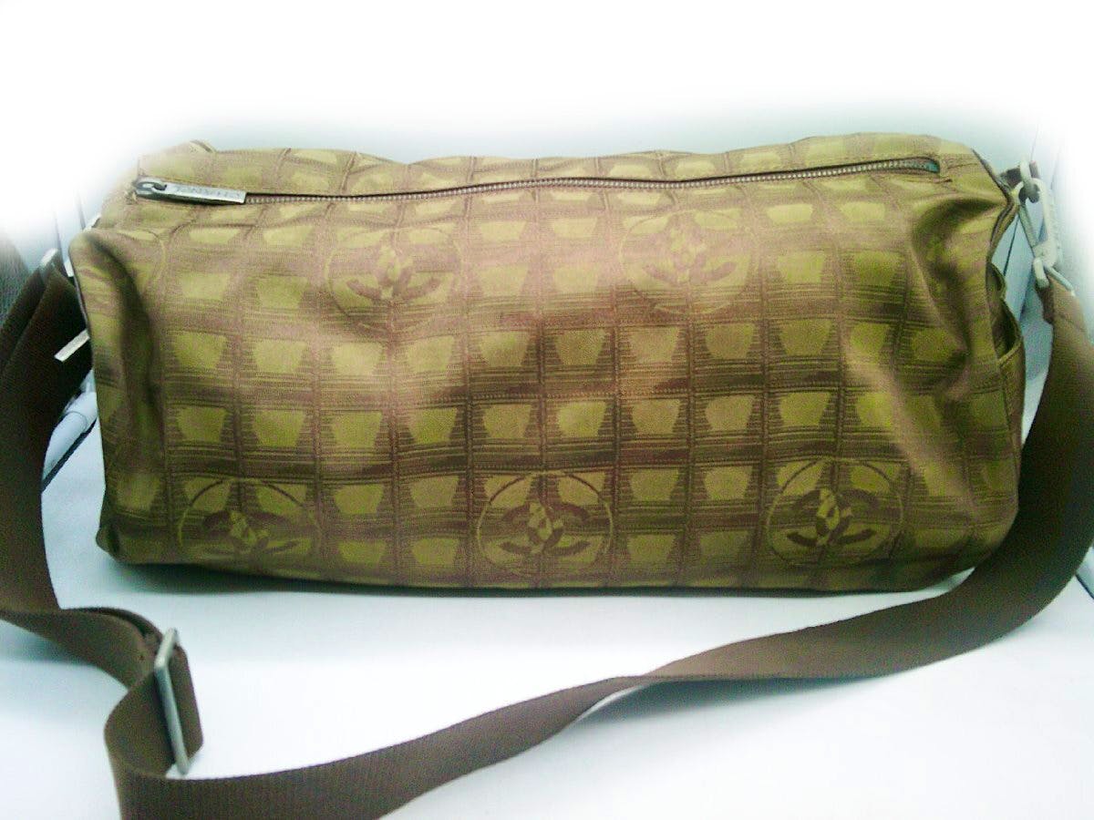 Khaki nylon shoulder bag with brown adjustable strap, zippered top, and patterned exterior.
