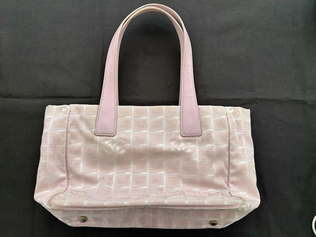 Pink CHANEL nylon tote bag with two handles shown from the front on a dark background.