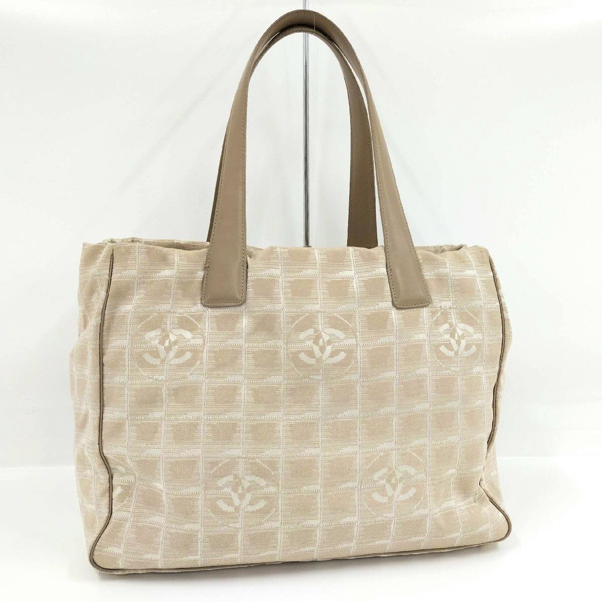 Beige CHANEL New Travel Line nylon canvas tote bag front view with dual leather handles and CC motif.