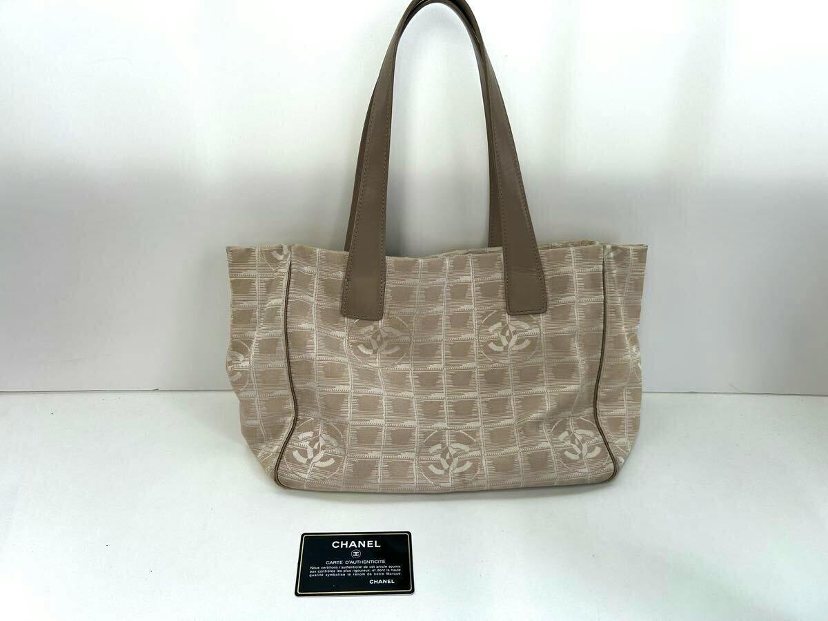 Front view of a beige CHANEL New Travel Line tote bag with leather handles displayed with its authentication card below.