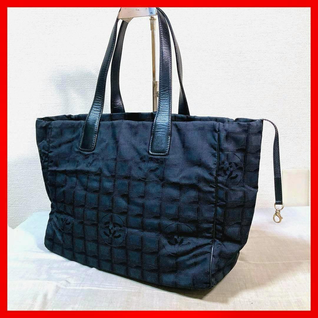 Black nylon CHANEL New Travel Line tote bag with leather handles and a quilted square pattern shown on a flat surface.