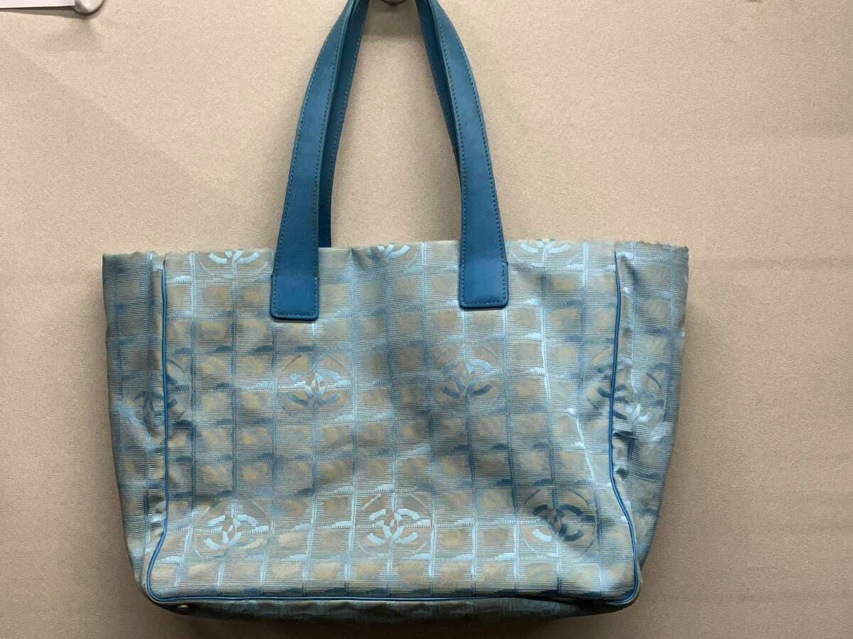 Front view of a blue CHANEL nylon New Travel Line tote bag with twin top handles and repeating CC logo pattern.