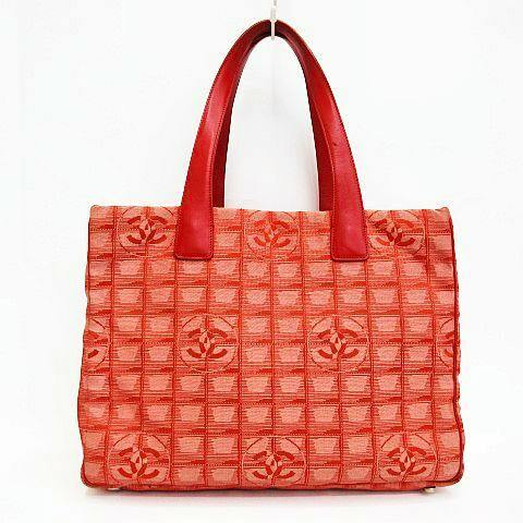 Front view of a red CHANEL New Travel Line MM tote bag showing woven CC logo pattern and red leather handles.