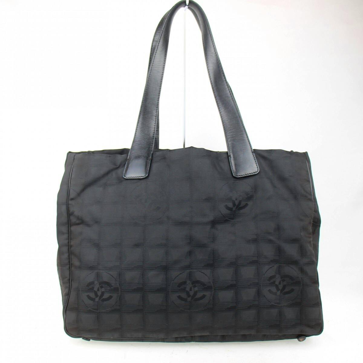 Front view of a black Chanel nylon tote bag with leather handles and a repeating CC logo pattern.