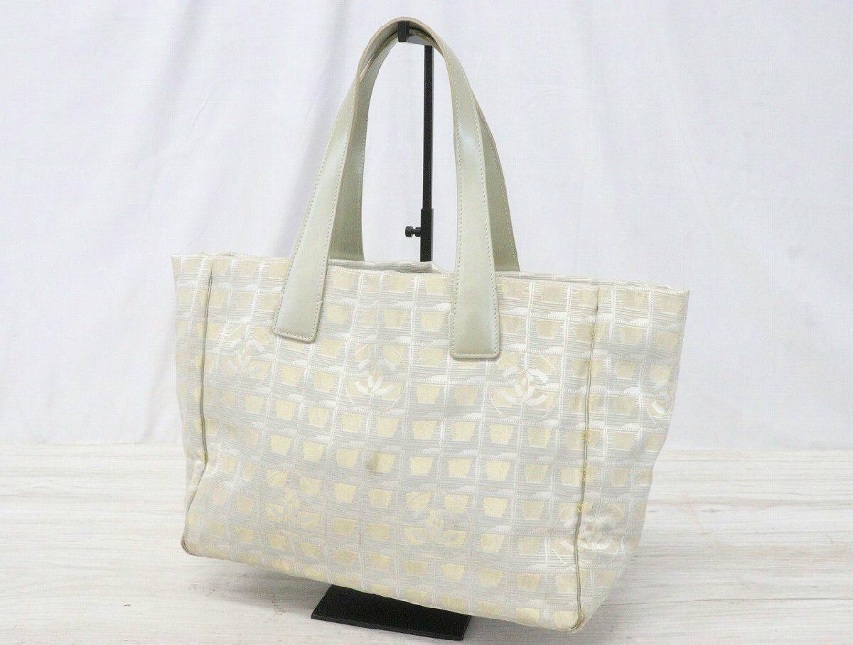 Front view of the CHANEL New Travel Line MM tote bag in light nylon jacquard with leather handles displayed on a stand.