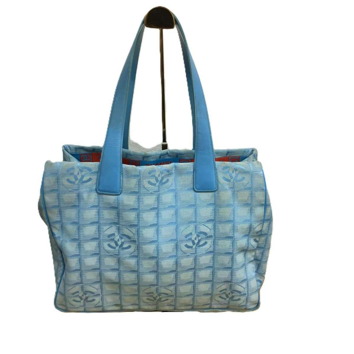 Blue Chanel New Travel Line tote MM in jacquard with repeated Coco Mark pattern and two shoulder straps on a white background.