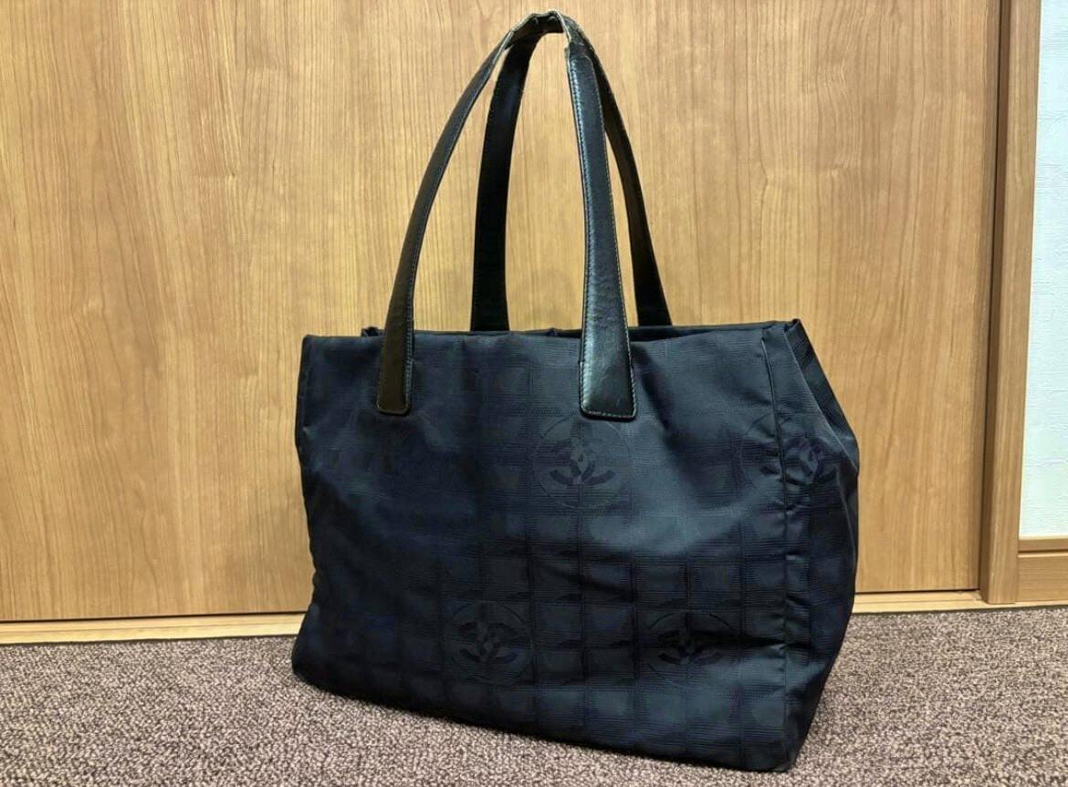 Black CHANEL New Travel Line MM nylon tote bag standing upright showing the full exterior and dual shoulder handles.