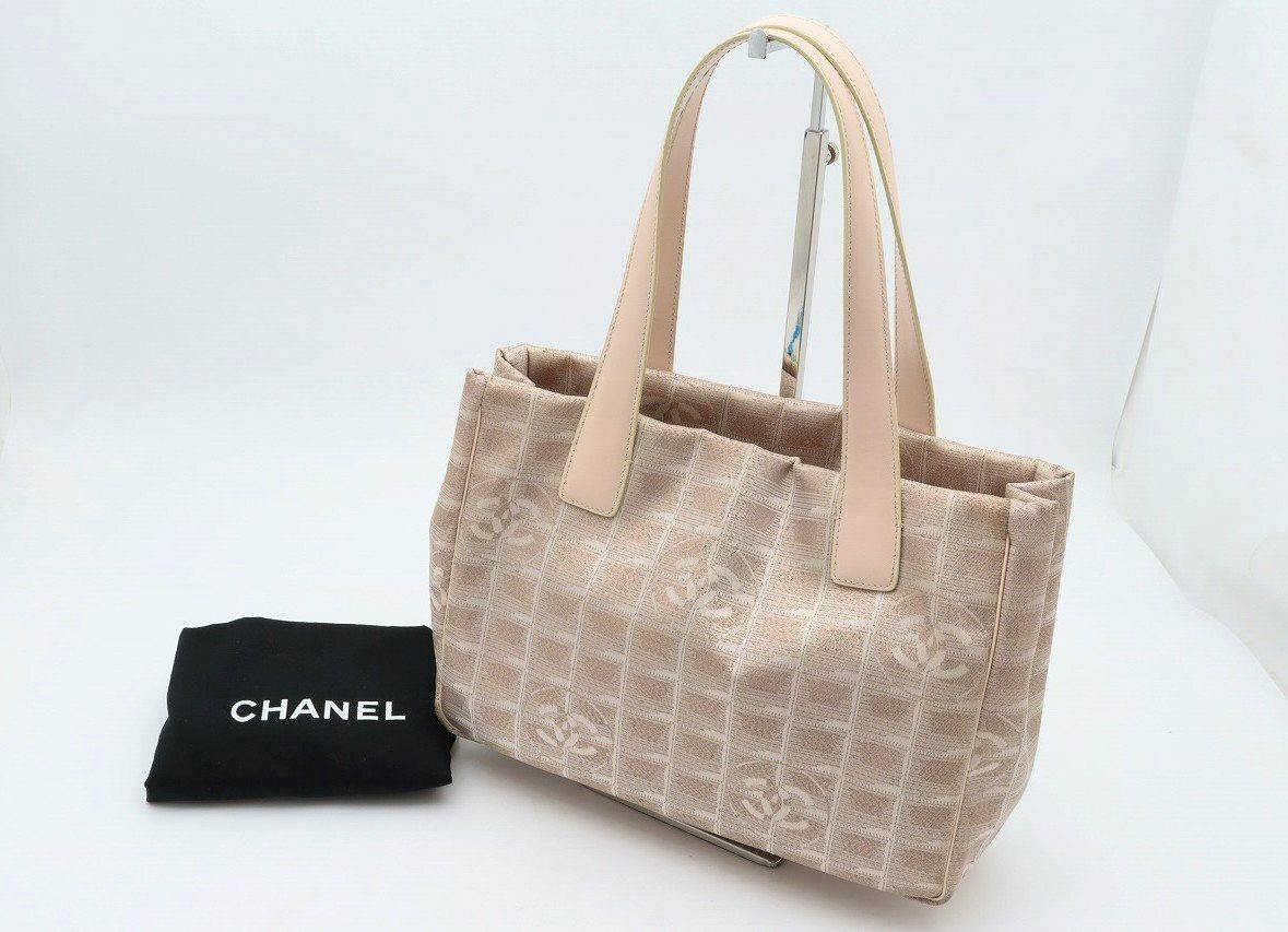 Pink-beige Chanel nylon jacquard tote bag with leather handles shown beside a black CHANEL dust bag.