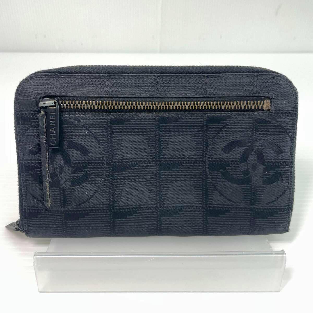 Front exterior of a black CHANEL New Travel Line canvas zip-around long wallet showing the CC pattern and an exterior zipper pocket.