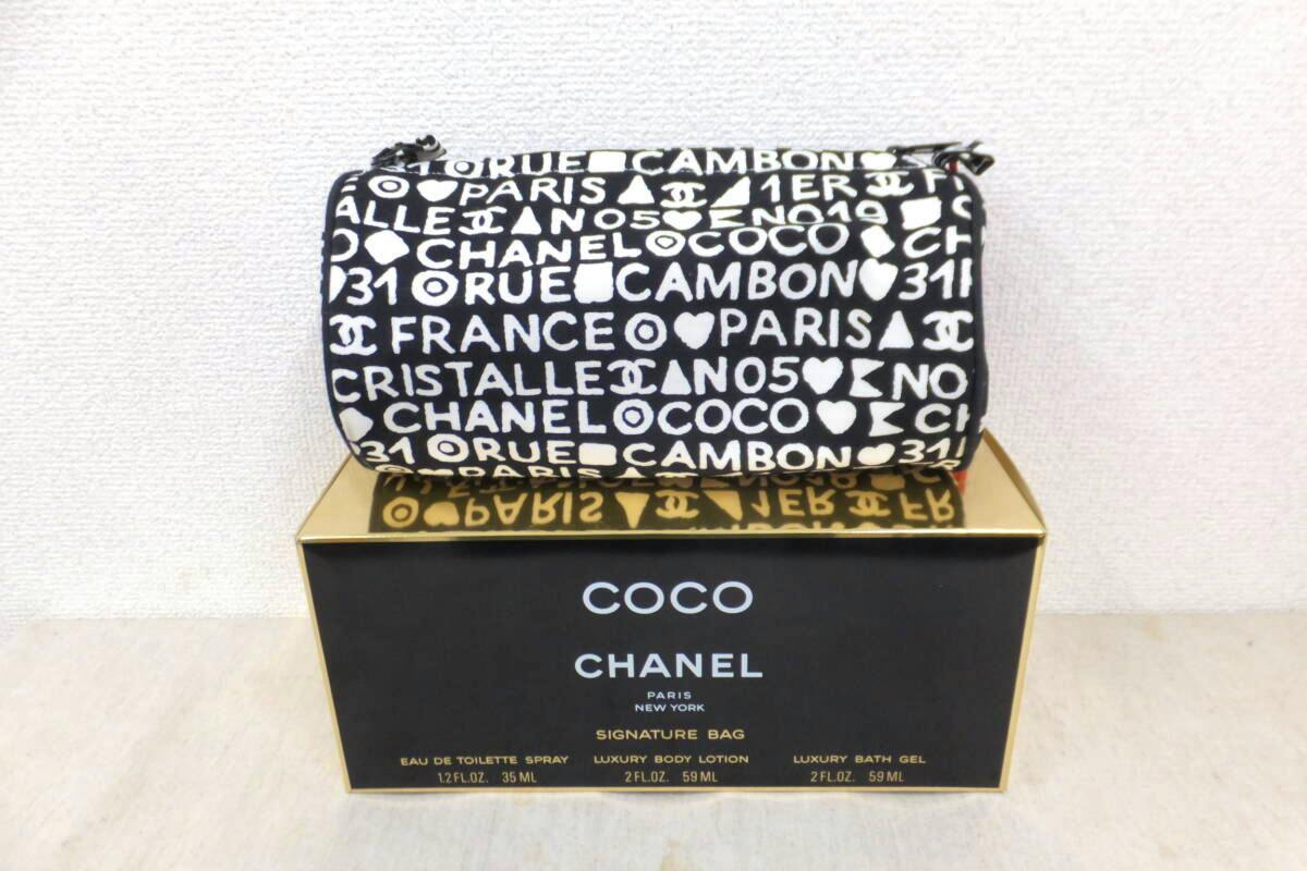 Black and white cylindrical CHANEL canvas pouch with logo print placed on a COCO CHANEL box.