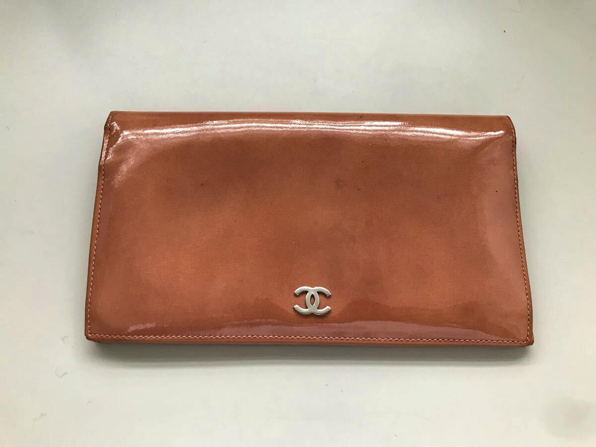CHANEL orange long two-fold wallet shown closed on a plain background with a silver interlocking CC logo on the front.
