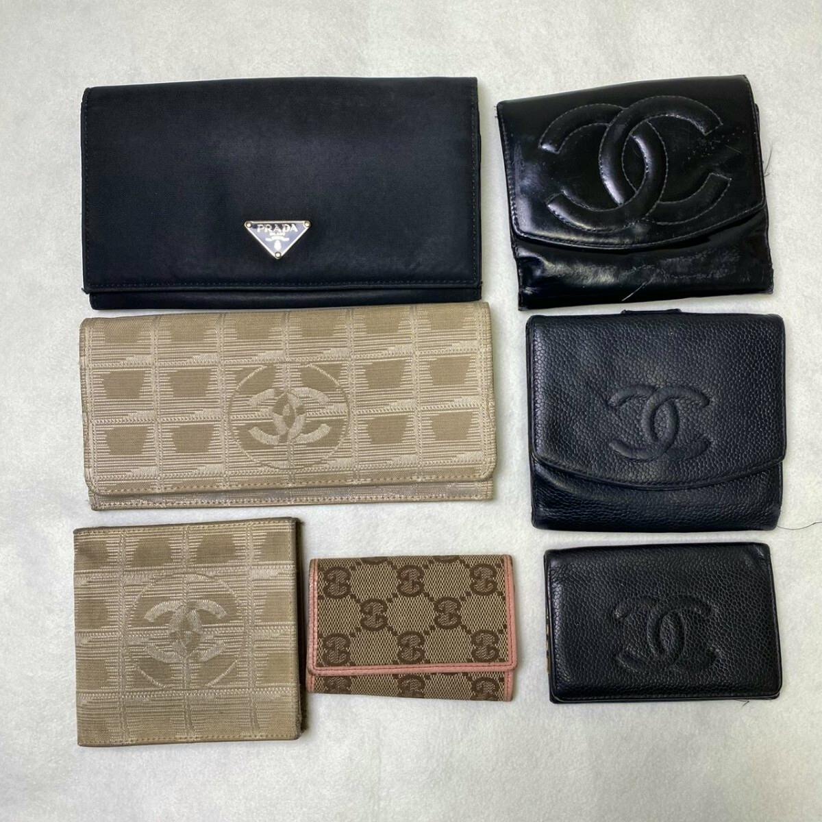 Seven wallets from brands such as Prada, Chanel, and Gucci arranged on a light surface.
