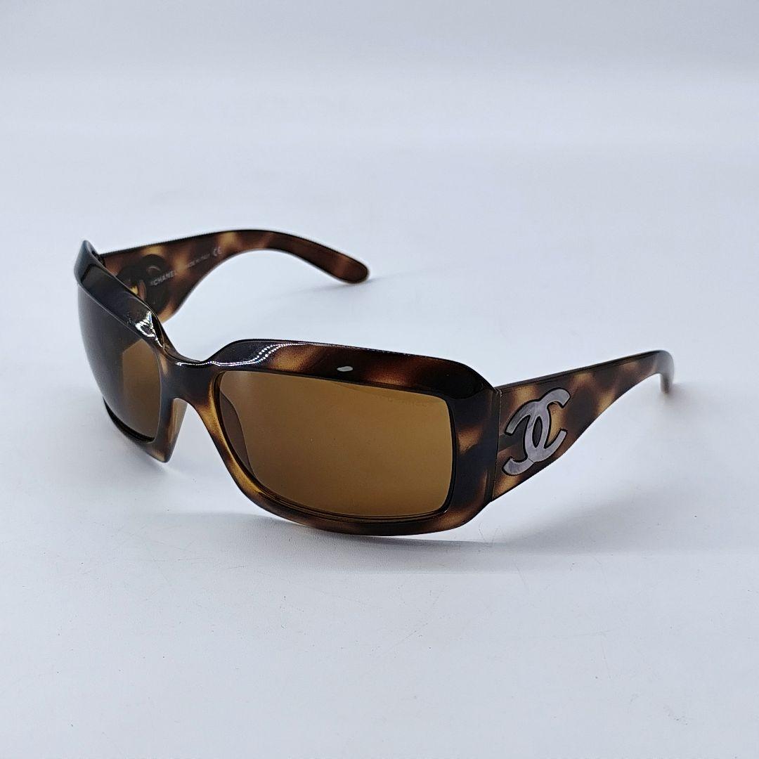 Brown tortoiseshell square sunglasses with large Chanel double-C logo on the temple, shown at an angled front view.
