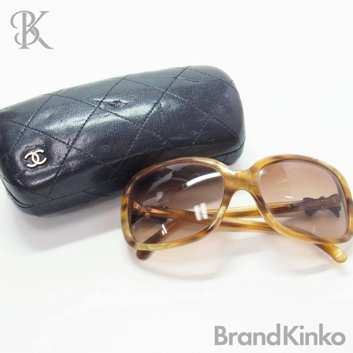 Tortoiseshell plastic CHANEL sunglasses displayed next to a black quilted CHANEL case on a white background.