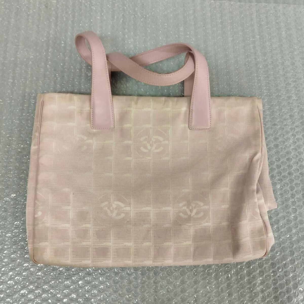 Light pink canvas Chanel Travel Line tote bag photographed flat showing the front panel and leather shoulder handles.