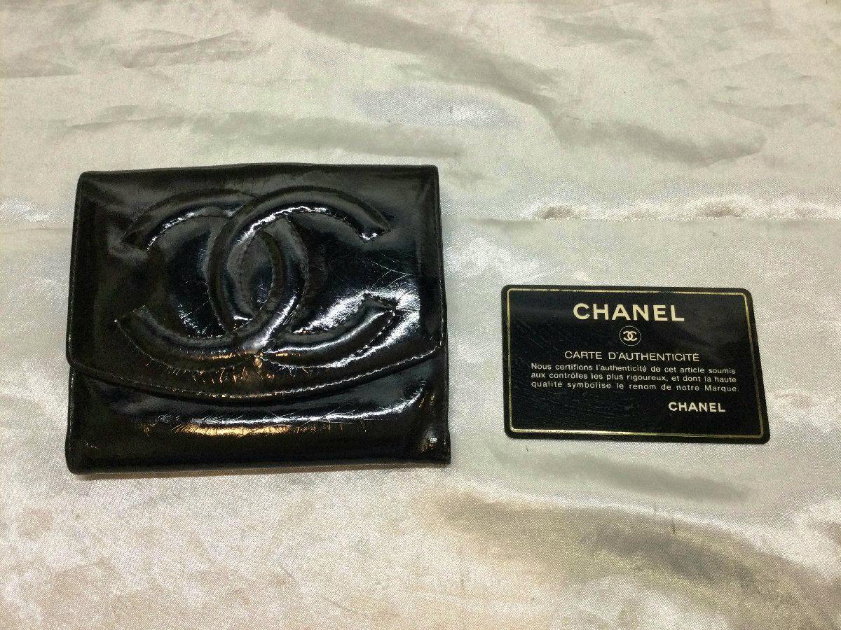 Black patent leather Chanel two-fold wallet with a raised CC logo shown beside an authenticity card.