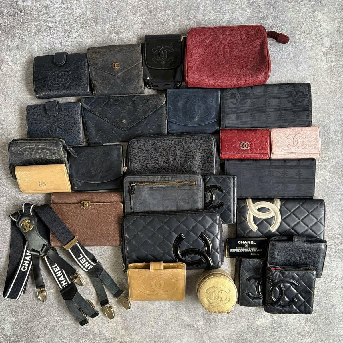A collection of CHANEL wallets and small leather accessories arranged on a gray surface showing various colors and styles.