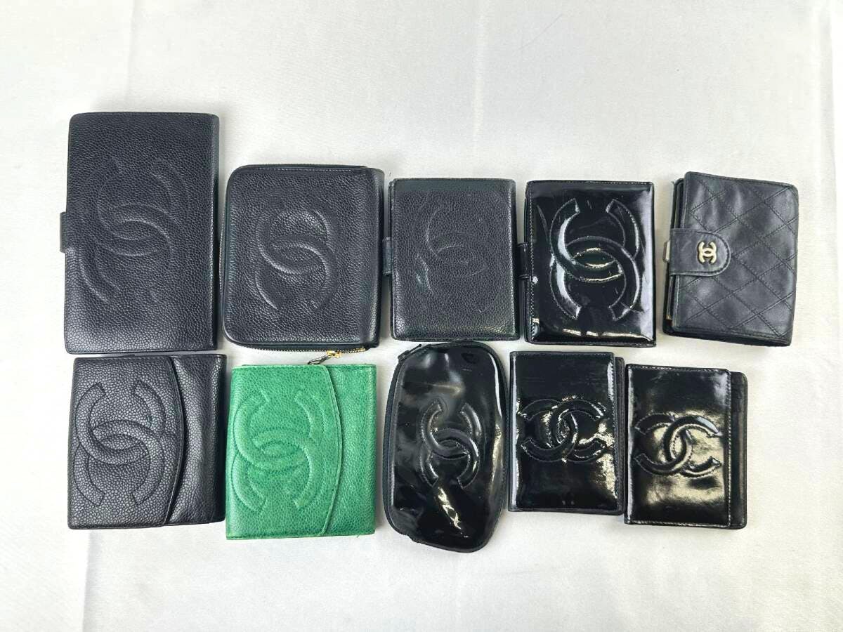 Ten wallets in black and green with visible Chanel CC logos arranged on a white surface.